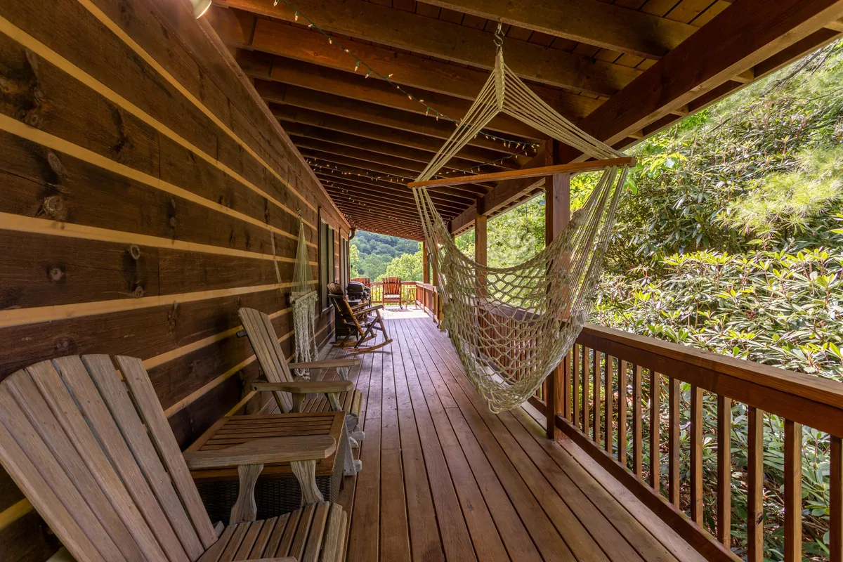 An inviting scene with a hammock and wooden chairs on a wooden deck, bordered by rustic railings and encircled by the tranquility of the woods. The area is perfect for relaxing, reading, or gazing at the stars after a day of adventure.